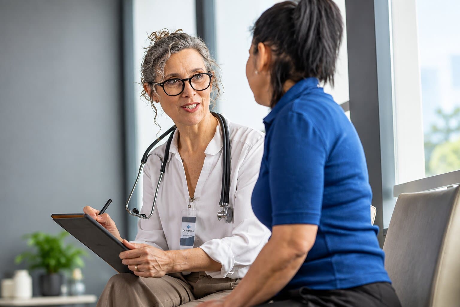 A physician with a stethoscope listening to a patient during a consultation