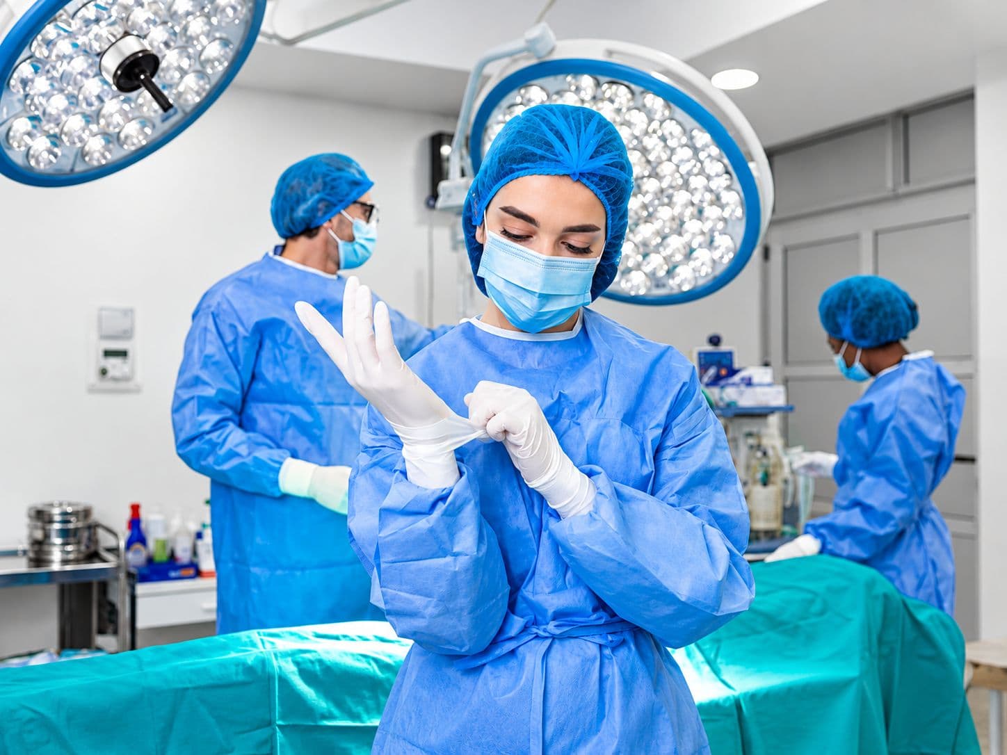 A surgeon pulling on sterile gloves in an operating room before a procedure